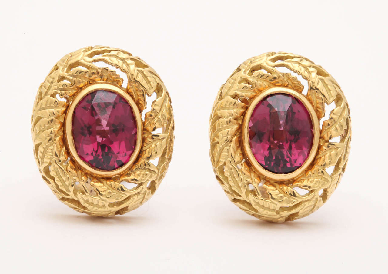 Surrounding the oval raspberry colored rhodolite garnets is a delicately carved bombe border of tiny leaves.  It gives the earring a lacey appearance without sacrificing the impressive size.The garnets are checkerboard cut and bright and  lively. 