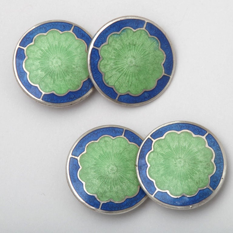 American Art Deco sterling silver cufflinks with central scalloped green guilloche enamel framed in a blue enamel border.

Hallmarks: STERLING/ B back to back with an R

*Variety of other Art Deco sterling silver and guilloche enamel cufflinks