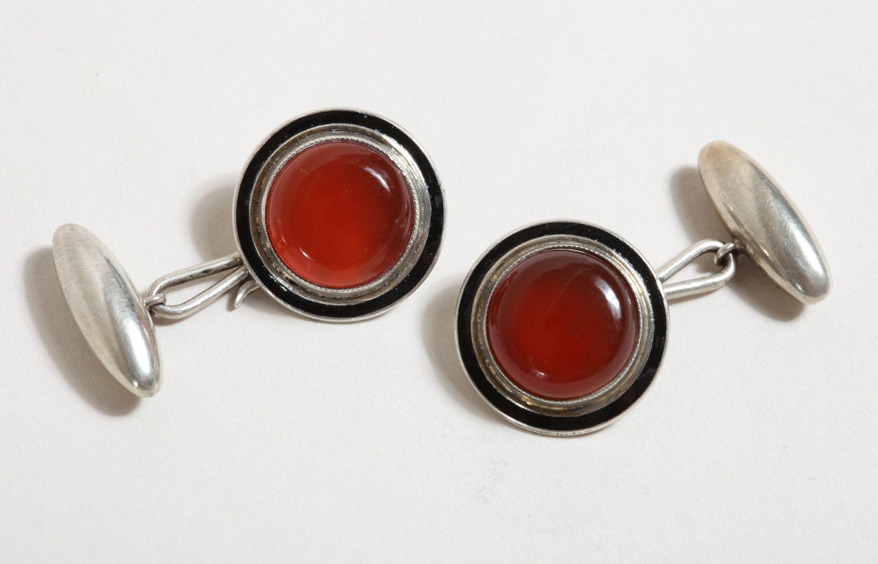 Circular with dome of carnelian with a black enamel border and with torpedo link.
Hallmarks:  925 silver/ Birmingham/ 1908/ STERLING