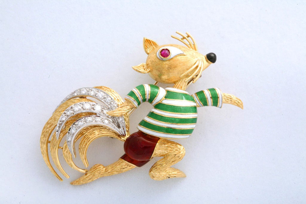The brooch depicts a sculpted 18k gold squirrel wearing a green and white guilloché enamel sweater and red shorts. The tail is highlighted with over one carat of brilliant diamonds. 

This piece is marked ITALY ML 18k, but is identical to the one