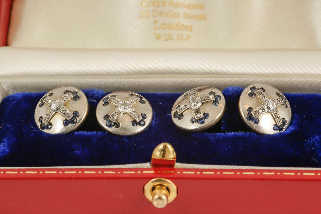 Antique pair of platinum faced double sided cufflinks mounted in 18 karat gold, set with a brilliant and rose-cut diamond cross centre, terminating with twelve sapphires to each side in a Fluer de Lys pattern. Circular in shape with French