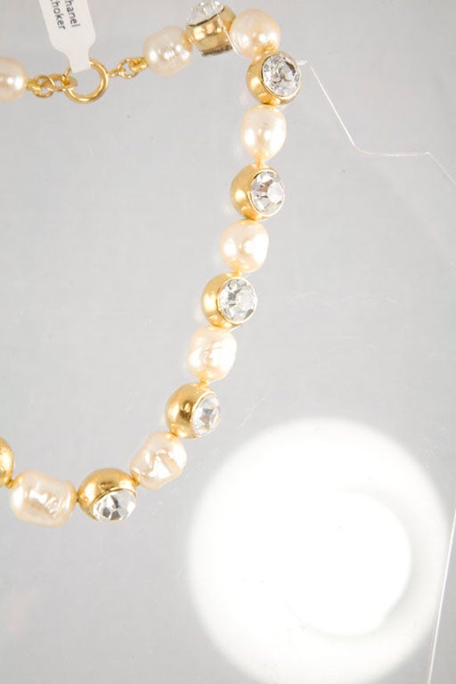 A stunning gold tone and glass pearl necklace, accented with large clear faceted crystal rhinestones.  Each rhinestone is set in a gold plated bead.  Stamped and marked Chanel made in France.