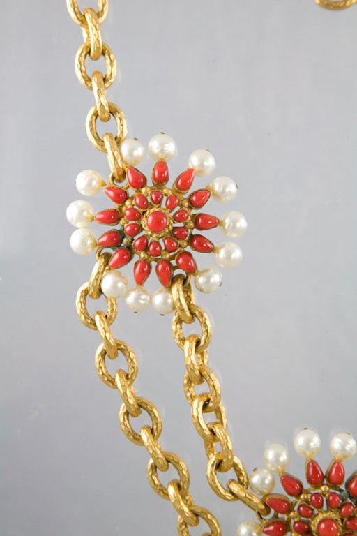 This beautiful and amazing vintage necklace by Chanel features four clustered poured glass red coral squash blossoms surrounded by multiple poured glass pearls, each suspended on a hand chased double strand gold plated chain. A true beauty.  This