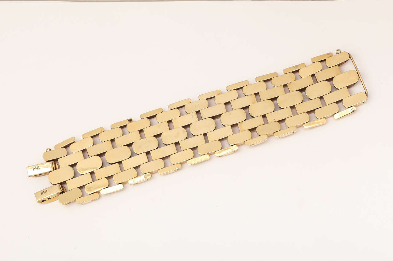 Retro bracelet in 14 Kt. gold . At the edges the border is diagonally ridged. In one line are plain gold jelly bean links followed by plain less puffy links. At center the texture is again ridged with engraving , on puffy jelly bean shapes. Safety