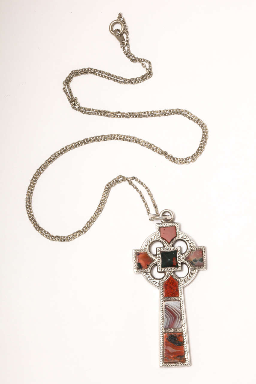 The handsome celtic form of a cross with a circular top is set with agates of arrow or shield form, all which point to the pillow shaped central agate. The stones in the stem of the cross are orange and green as are the agates of the circle, all