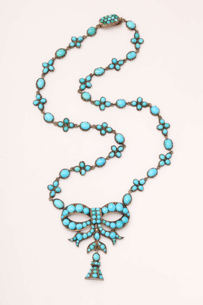 Beautiful and symbolic, this turquoise and gold necklace, c. 1860, expresses "think of me" in more ways than one. Small forget-me-not flowers are links on the persian turquoise chain that suspends a bow and a bell. Forget me nots stand for