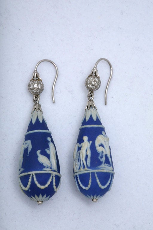 These earrings are in the traditional Wedgwood style: white neo-classical figures in bas relief are depicted against the famous Wedgwood blue background. The tops of these earrings are accented with pavé-set diamonds, with a small diamond on the