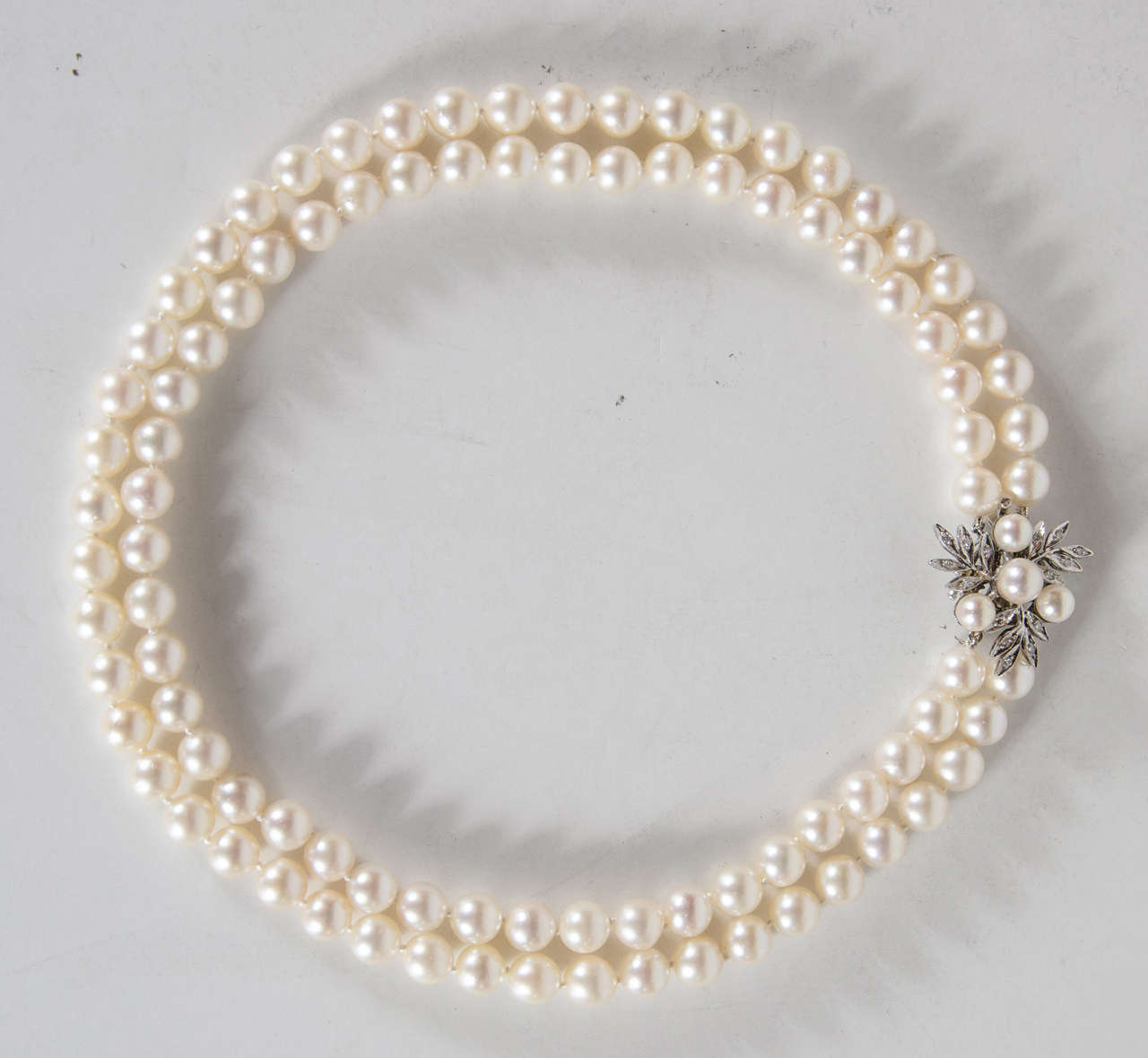 This beautifully matched double strand of Pearls feature 6.5 millimeter pearls in a lustrous creamy white. The clasp is 14k white gold set with diamonds and 4 pearls in a stylized floral design.Thet have also just been restrung.