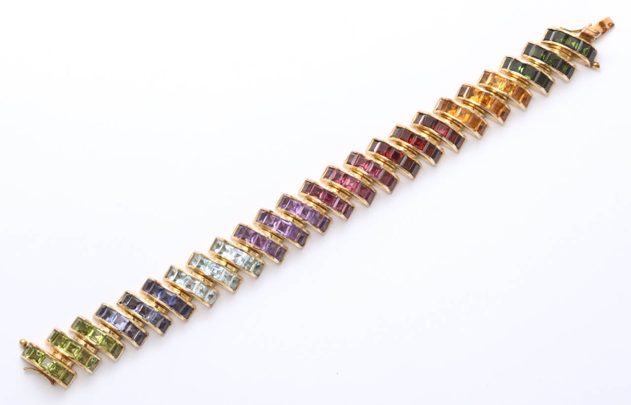 Bezel set Bracelet in 14kt Rose Gold with Rows of Peridot, Sapphire, Aquamarine, Amethyst, Amandine Garnet, Rubelite, Citrine & Green Tourmaline.  Stones are square set  and invisibly set in a half round bezel setting that is  connected by a 1/2