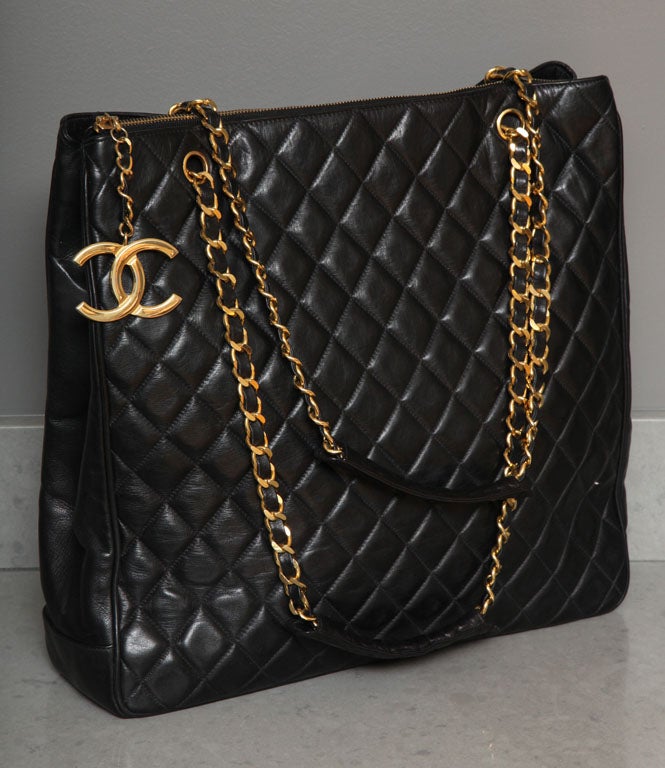 Chanel black tote bag with quilted details and iconic CC logo charm pull.