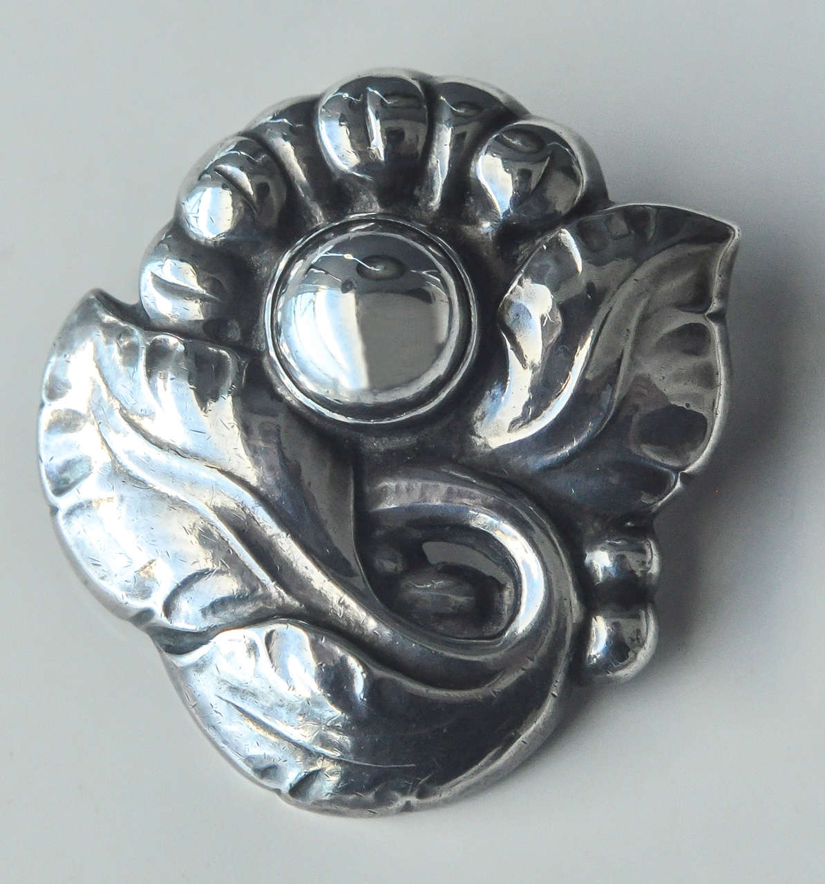 This stylized flower brooch is a very early example of Georg Jensen jewelry dating from c. 1909-14.  Pieces from this early period are scarce.