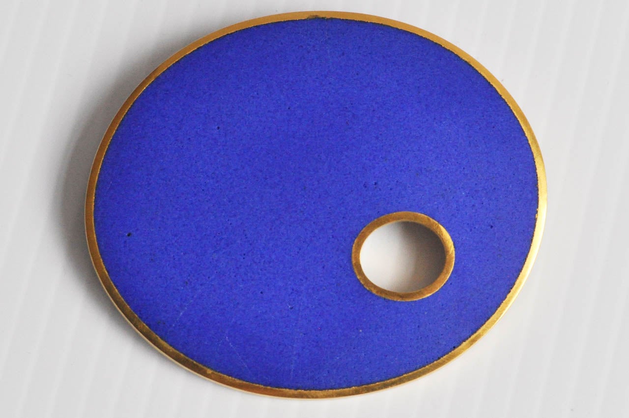 A hand-wrought pin by the German-born artist John Iversen, a master craftsman, whose studio is in New York.  This brooch is from his Enamel series; it's ovoid shape was inspired by the forms of pebbles.  The organic simplicity of the design and the