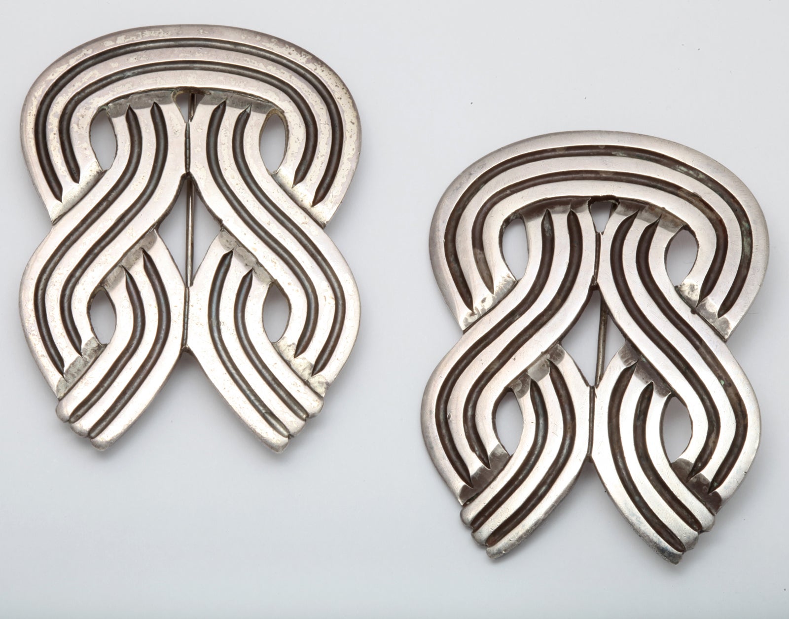 Double eights, four streams, four knots ,however you see the design, you will see the strong statement that these brooches make. They are hand crafted and deeply engraved into swirling lines that have been anodized to emphasize their curves. I tried