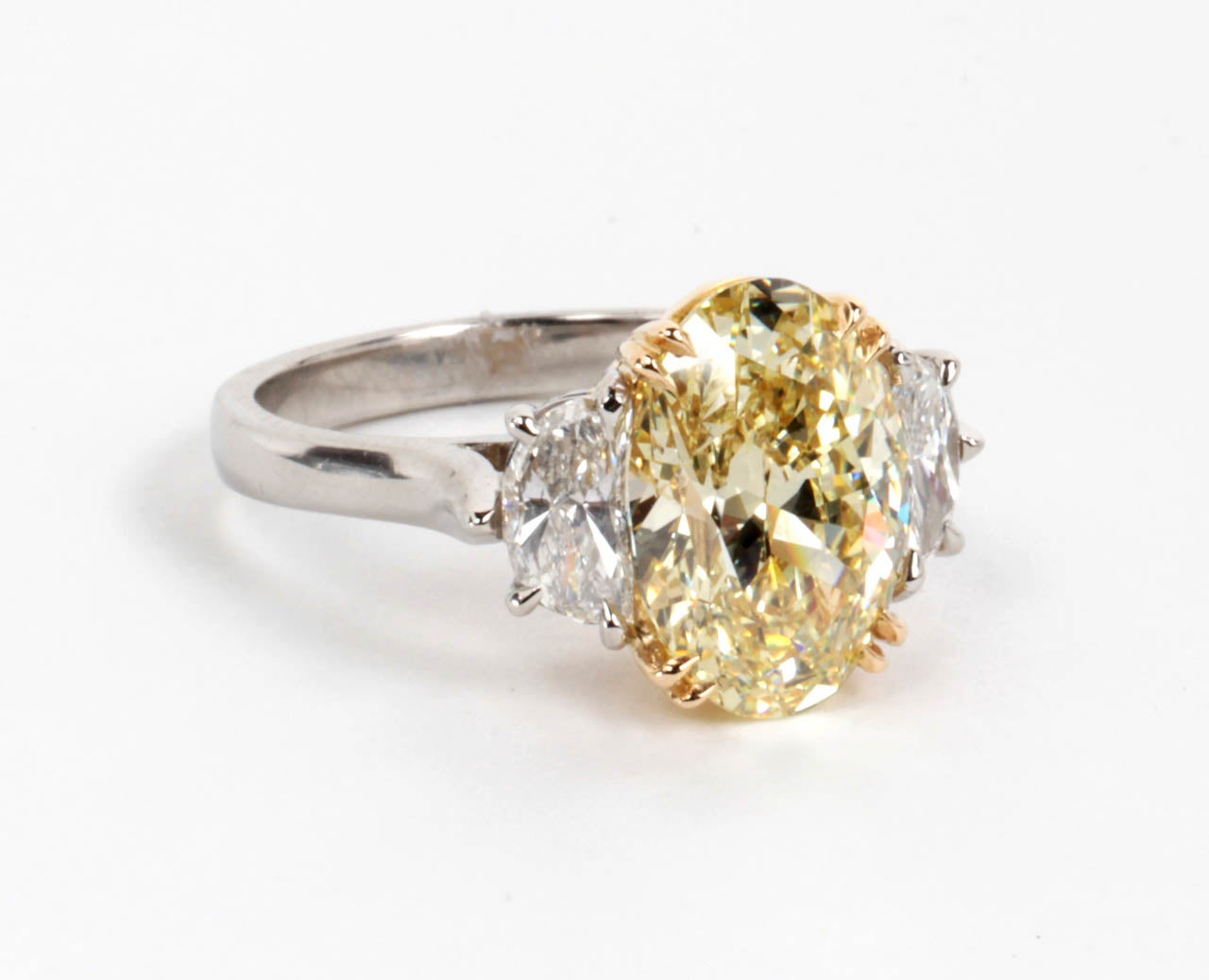 GIA certified 3.33 carat oval cut Fancy Yellow, VS1 clarity center diamond set in custom handmade, platinum and diamond mounting. .84 carats of half moon cut white side diamonds.