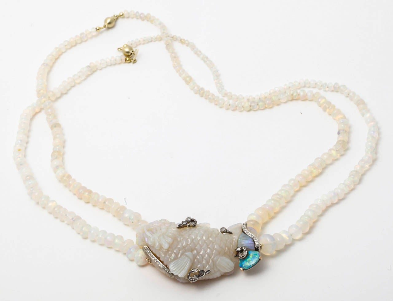 A double opal bead necklace centrally set with an opal fish carving, surrounded by a golden framework set with diamaonds.

All of our prices exclude VAT.