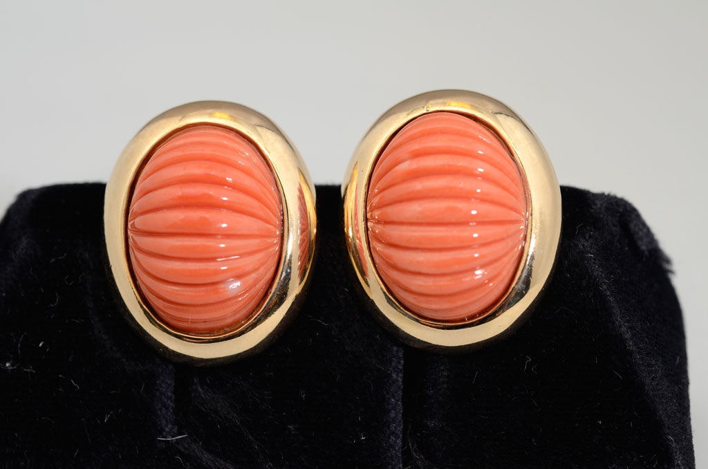 A pair of coral earrings set in 14 karat gold.  The fluted coral stones measure 19.4 mm by 10.9 mm and weigh appoximately 11.4 dwt.  The earrings are signed on the interior 