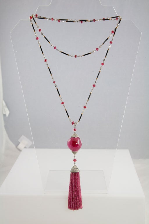 The necklace is composed of repeating links consisting of spinel beads, bezel-set diamonds and gold bars decorated with black and brownish-red enamel. The bottom portion of the sautoir contains a removable beaded spinel tassel with a pierced diamond