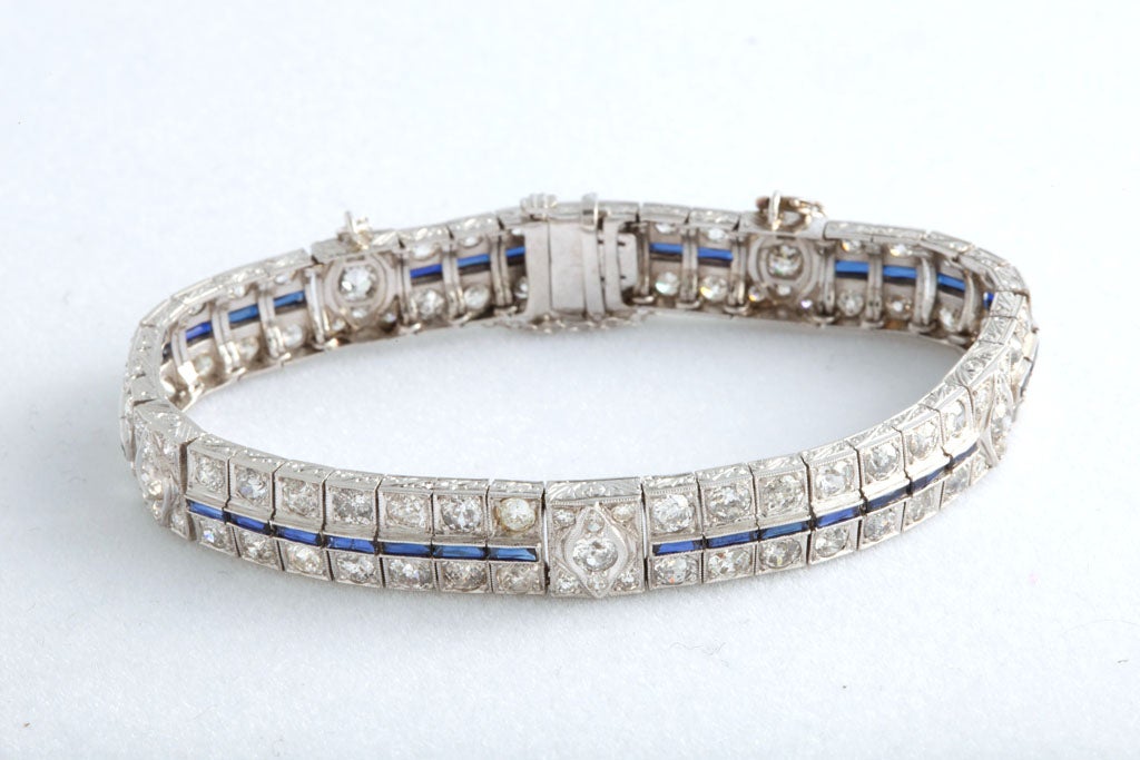 This Art Deco line bracelet has lovely etching on the side of the links.  The links have 2 diamonds separated by a channel set sapphire.  Additional larger diamonds are interspersed in the design.  The mounting is platinum.  The diamond weight is