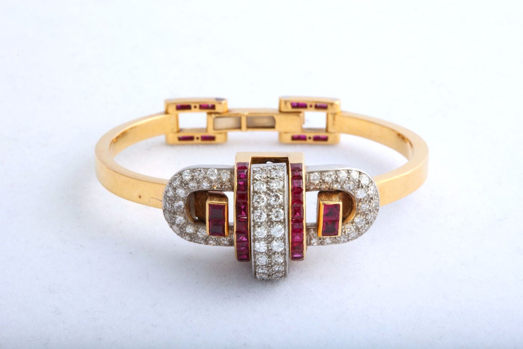 An elegant and refined bracelet with great Art Deco style in 18k gold set with diamonds and calibre-cut rubies. The clasp is also set with rubies, and the central motif cleverly conceals a watch.