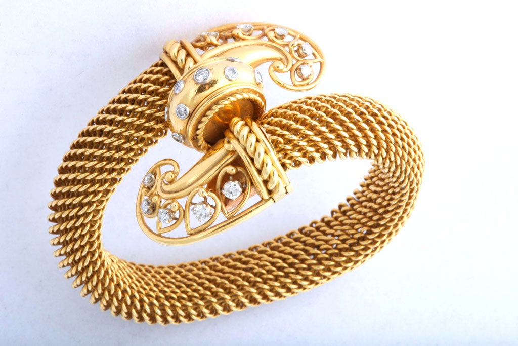 A classic example of great 1950's design in 18k gold flexible mesh-work and diamonds, with the back-wind watch hidden - it is the central disk-shaped element that easily pops out. Back-wind watches were quite costly and difficult to make, and were