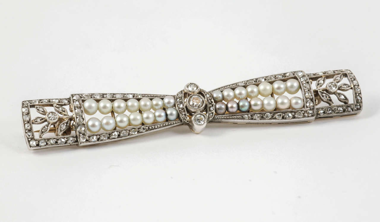 Finely made platinum mounted natural pearl and diamond bow brooch. French, circa 1910.
