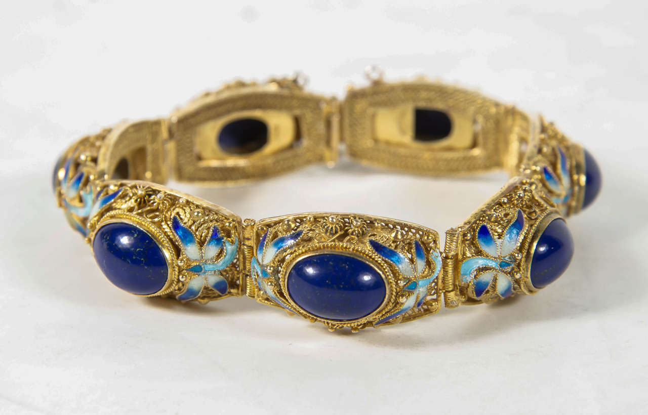 This luxe bracelet features 7 links set with an oval cabochon lapis lazuli stone accented with stylized enameled dragon flies and filigree work. It is gold washed over sterling silver and it is marked 925. This can be worn to the most elegant