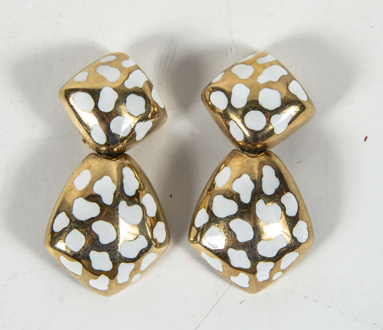 These drop earrings feature an organic form wrought in 14 k yellow gold with amorphic inlays of white enamel. These earrings would particularly look exceptional on in the summer.They are clip on earrings but can be converted to posts as well. These