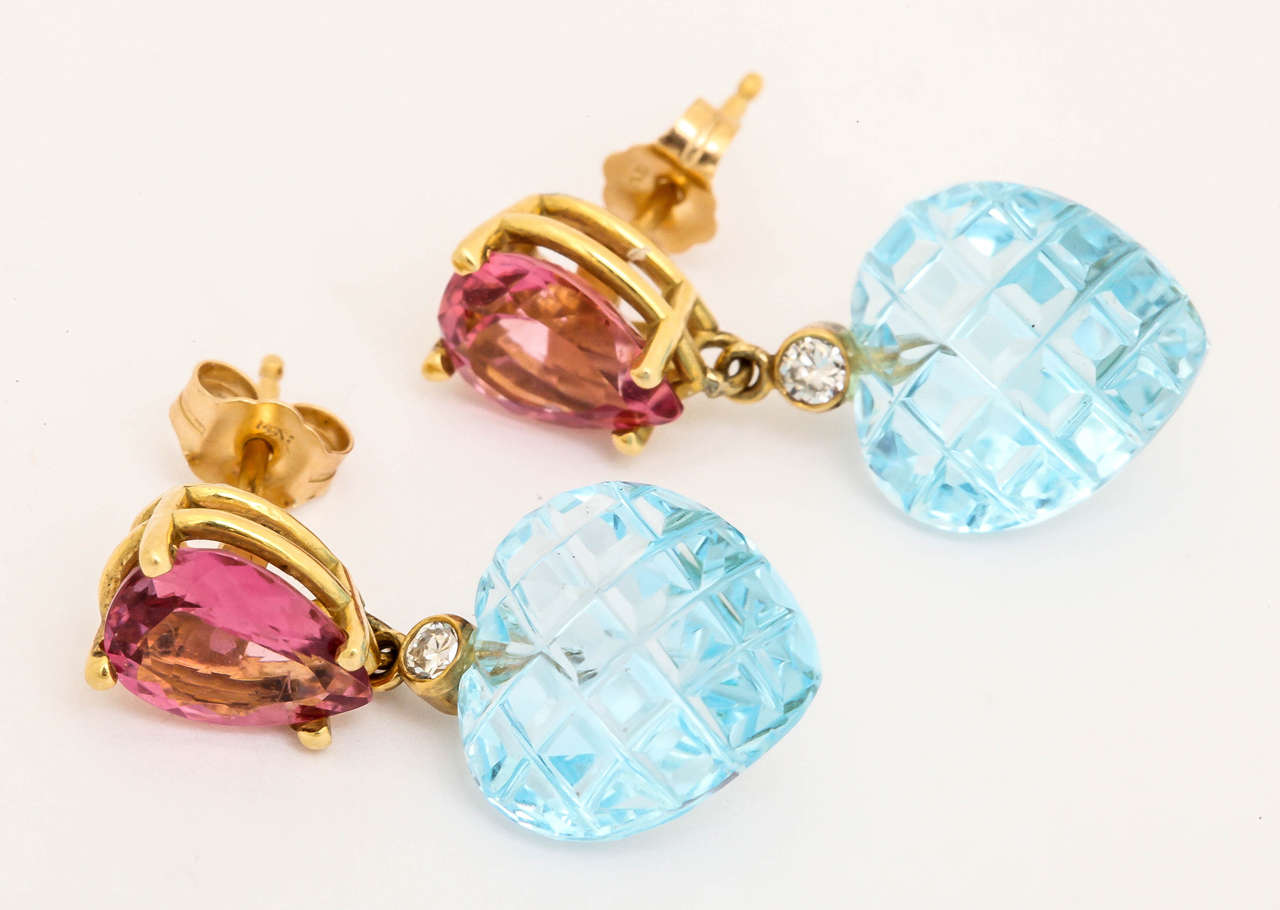 The pear shaped pink tourmalines are a wonderful bright pink and they are 8mm by 10mm. Dangling from the tourmalines is a bezel set 5 pt diamond and then  uniquely checkerboard cut blue topaz. The color combination is delicious and a great idea for