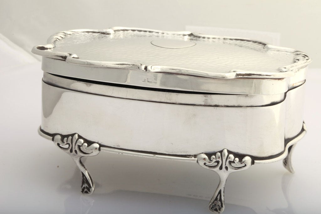 Footed, sterling silver, hammered jewelry box, Birmingham, England, 1906, H. Matthews - maker. Lined in dark green velvet. Underside of lid is vermeille; underside of box is covered in leather. Measures: 5" wide x 2 3/4" high 4" deep.