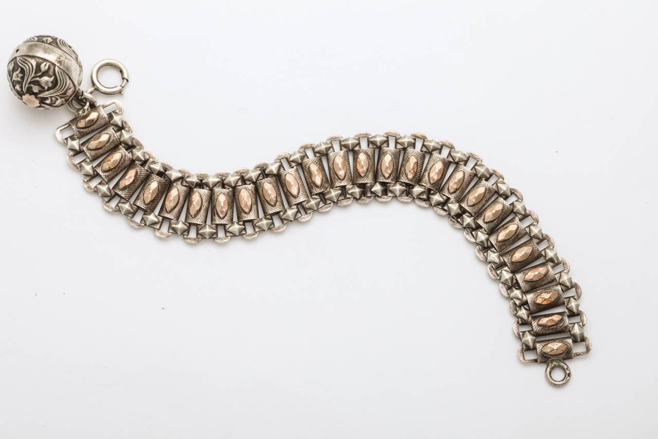 Pretty as a picture is this French 19th century bracelet. An orb with dancing tulips is playfully suspended from the textured silver. The links are flexible and the bracelet comfortable..Central on each silver rectangle is a raised golden diamond