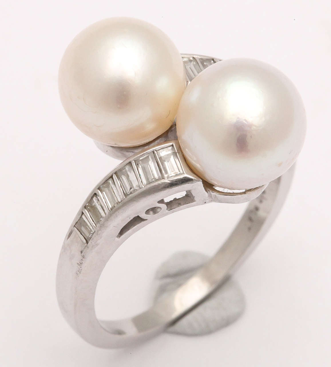 Crossover Platinum mounting  set with a Pair of 9mm Cultured Pearls, and detailed with 6 graduated Diamond Baguettes on either side.  Perfect for a chic pinky ring or non Diamond Engagement Ring.  Size 7 will fit perfectly or it can be sized up or