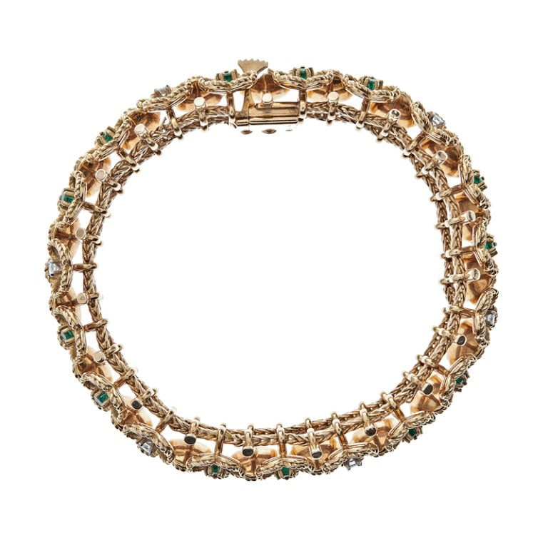 A beautiful buttercup floral design made in 18k yellow gold circa 1960. This wonderfully crafted bracelet was meticulously created, highlighted by a combination of diamonds and emeralds at the heart of each five pedal buttercup setting. 1.30 carats
