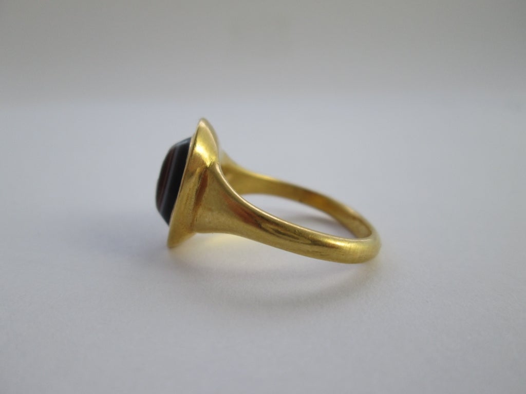 PLEASE NOTE: OUR PRICE IS FULLY INCLUSIVE OF SHIPPING, IMPORTATION TAXES & DUTIES

Three layered eye agate, size of the stone: 11 mm Yellow gold unmarked but tested 22Kt gold.

The stone depicts a bearded Priapus facing left with a wineskin on