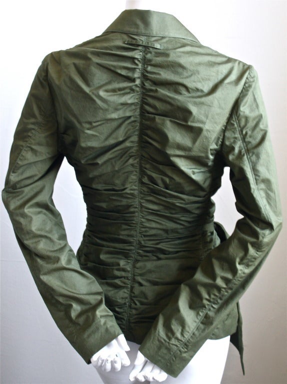 Beautifully ruched army green cotton jacket with side bow from Jean Paul Gaultier dating to the late 1990's. Jacket closes with two hidden snaps and a hook/eye.   Approximate measurements: shoulders 15