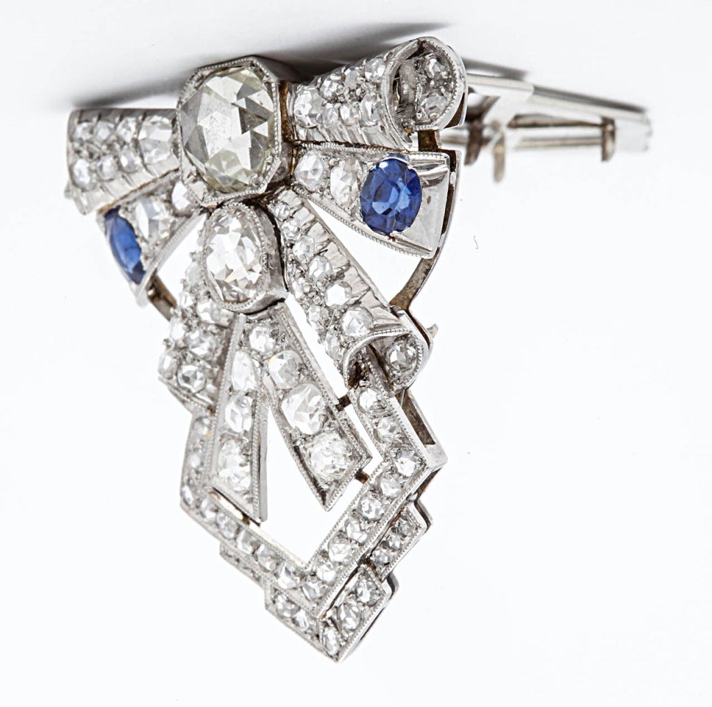 An Art-Deco white gold, sapphire and diamond clip brooch, the openworked 14 carat white gold Art-Deco clip brooch, set throughout with rose diamonds, an old-cut diamond and two  oval-shaped sapphires. Dutch, Art-Deco 1930s.

All of our prices