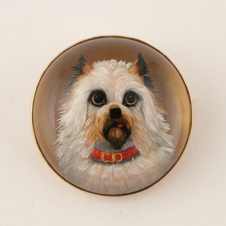 Eine englische antike Brosche aus 15 Karat Gold. Die runde viktorianische Brosche aus Essex-Kristall zeigt einen Terrier mit rotem Halsband, dem die Zunge heraushängt. Ein liebevolles Porträt eines geliebten Gefährten. Um 1880.

Unterschrieben,