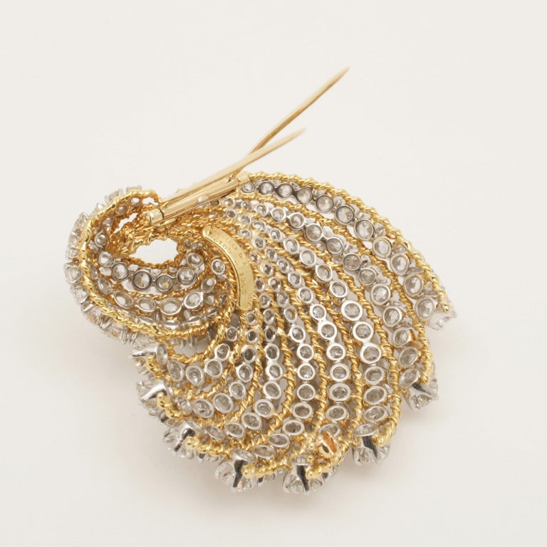 Van Cleef & Arpels has used twisted gold wire and graduated diamonds to create a swirl of movement in this quintessential 1960’s brooch.

The brooch features 132 round-cut prong set diamonds that graduate in size.  The diamonds have an approximate