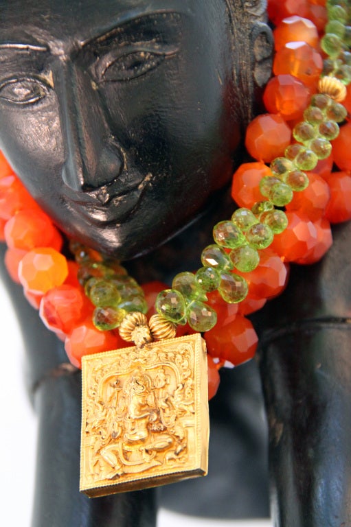 Intricate 22kt yellow-gold pendant of Indian god Ganesh on strands of peridot and carnelian beads.

Overall length: 18â??