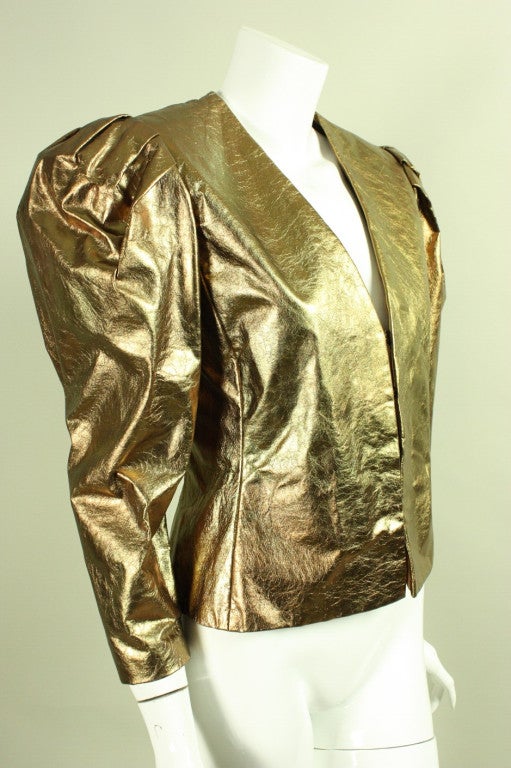 Vintage jacket from Bill Blass dates to the 1980's and is made of metallic gold leather.  It features massive leg-of-mutton sleeves that are gathered at the shoulders with shoulder pads to create additional fullness.  V-neck.  Center front hook and