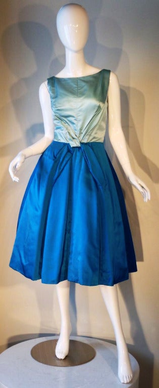 A fine vintage Luis Estevez cocktail dress. Contrasting blue silk satin item features a nipped waist and crinoline lined full skirt. Fully lined plus boned bodice features a sweetheart neckline and plunging back.