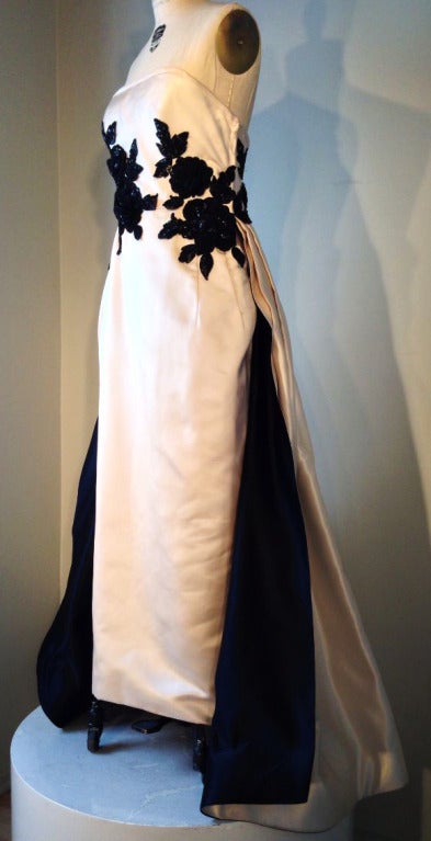 A stunning Odicini Couture evening gown. Ivory silk duchess satin item features heavy black Lesage embroidery plus a full train. Train double faced with jet black silk satin to match embroidery. Nipped waist and fully lined with a boned bodice
