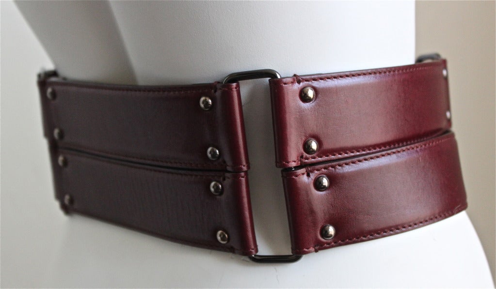Geometrically designed burgundy leather belt with antiqued brass hardware from Azzedine Alaia. Labeled a French size  size 75. Width is approximately 4