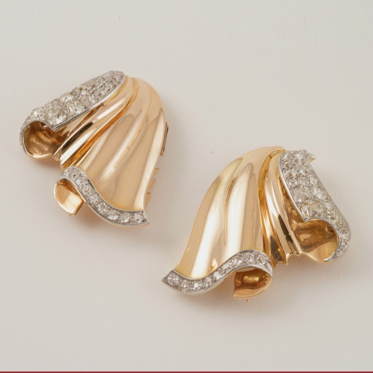 A French Retro 18 karat yellow gold and platinum pair of clips/brooch  with diamond detail. The pair of clips has 52 old mine-cut diamonds with an approximate total weight of 4.50 carats. Detachable pin back. 

Circa 1940's. 

Signed, French