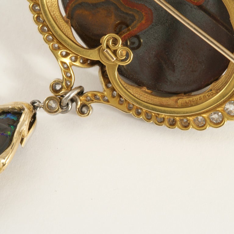 An American Art Nouveau 18 karat gold and platinum brooch/pendant with black opal, diamonds and enamel by Marcus & Co. The brooch/pendant has a center cabochon opal and 76 old mine-cut diamonds with an approximate total weight of 4.00 carats. Circa