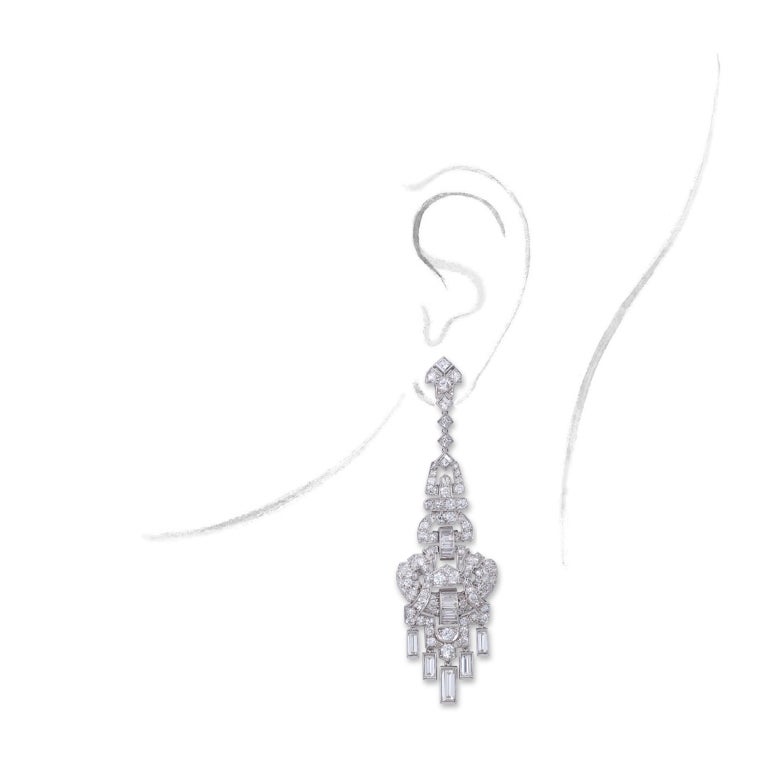 Each designed as an articulated open work pendent geometric motif, set with circular- and single-cut diamonds, to a baguette-cut diamond fringe, circa 1930, probably English.