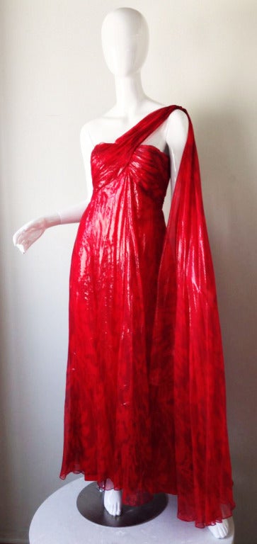 A fine vintage Bill Blass evening gown. Ethereally layered vivid red chiffon print with a slight metallic sheen fabric item features a ruched bodice with attached shoulder train. Item fully lined and zips up back.