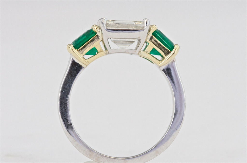The diamond weighs 2.28 carats and is certified by GIA as K color and VVS2 clarity, flanked by 2 Colombian emeralds weighing 2 carats. 18k white and yellow gold.

Ring size 6 and can be re-sized.