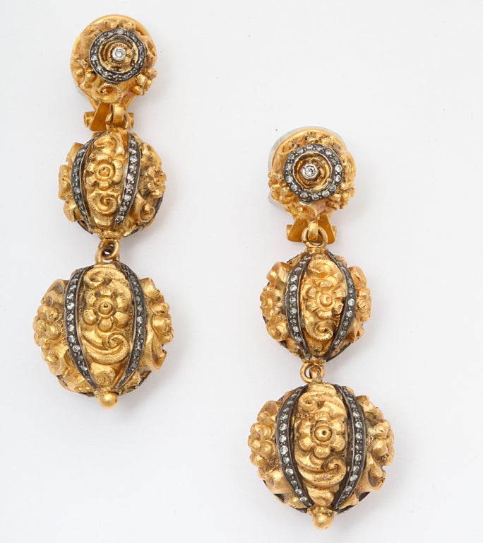 A pair of earrings composed of graduated ornate 22kt yellow gold flower beads. The beads are decorated with rhodium plated silver cages set with diamonds.
Length: 2.50 inches
Width: .80 inch
