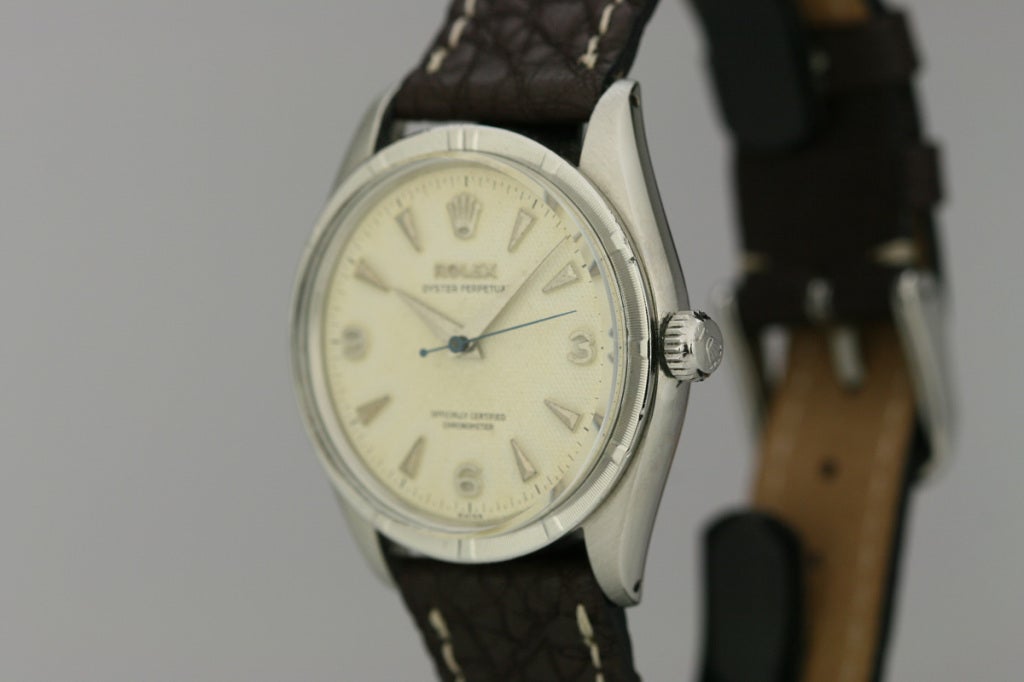 Rolex Oyster Perpetual chronometer wristwatch with textured ivory-colored dial, engine turned bezel, and automatic movement.