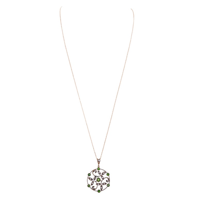 Sweet and feminine: 15-18k yellow gold and silver pendant, classic art nouveau design with a scrolling open-work design of diamond- and pearl florets and bezel-set demantoid garnets dancing around the border. Presented on a fine yellow gold, circa